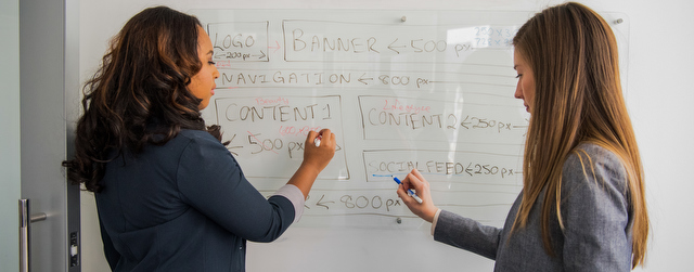 Two developers working at a whiteboard together